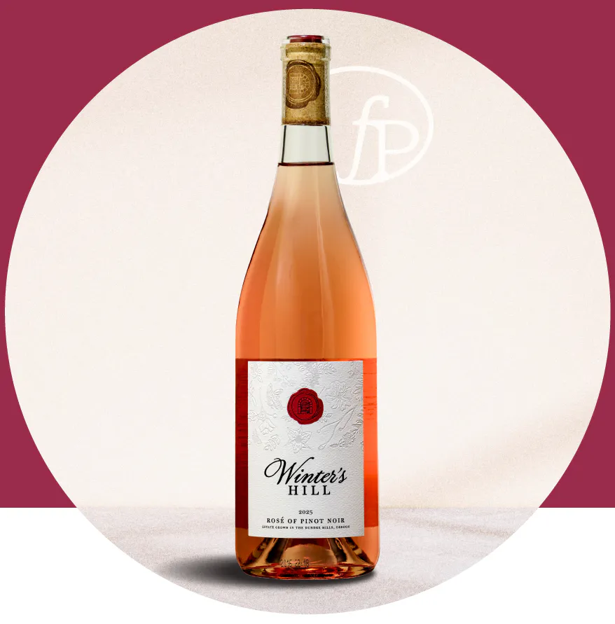 WHW26-0707 MM-FinalPour-July7_BottleLanding Bottle of Winter's Hill Rosé of Pinot Noir (2025) with pink liquid, on a light surface against a circular pink backdrop.